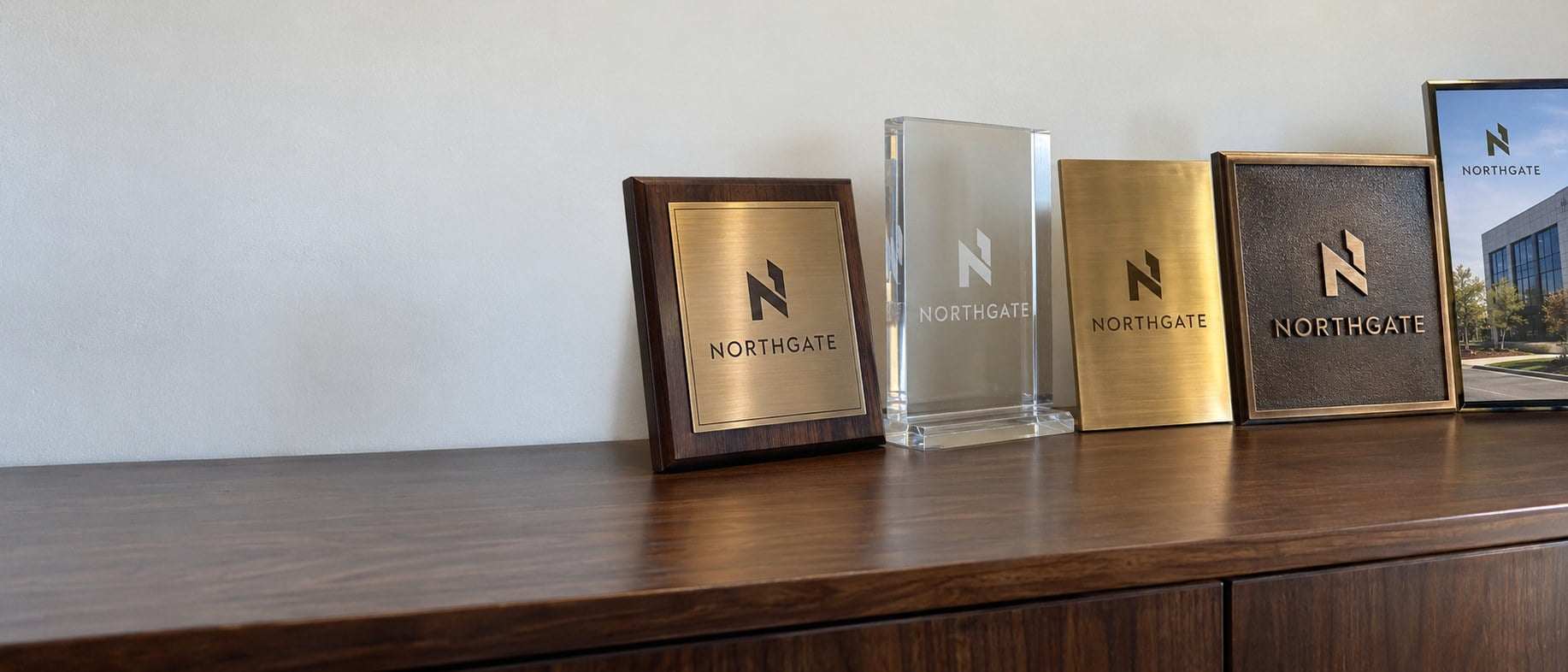 Custom engraved plaques with an award logo lined up along a walnut credenza